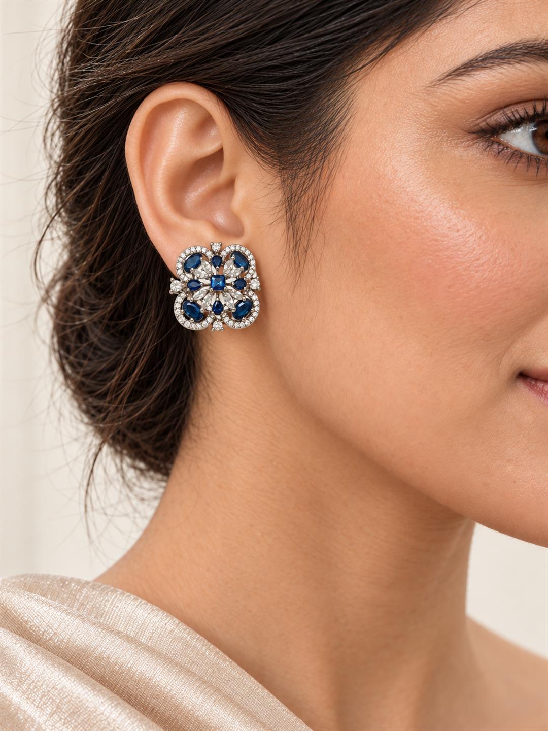 Blue four-leaf clover halo silver-plated stud earrings worn by a model